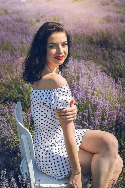 Attractive and young woman sitting in chair surrounded by lavender field