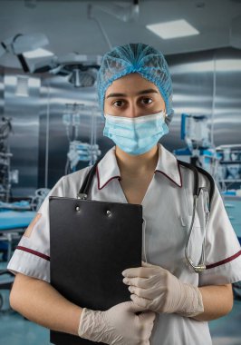 Modern kliniğin ameliyathanesinde ayakta duran doktor kadın doktor hasta için reçeteli pano ve kayıt bilgileri yazıyor. 