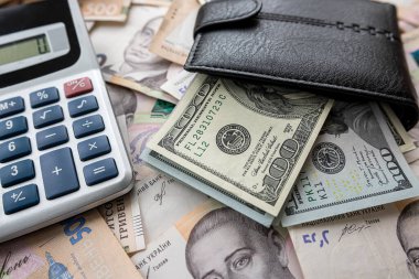 calculator with wallet on paper bills, Ukrainian hryvnias and us dollar exchange concept