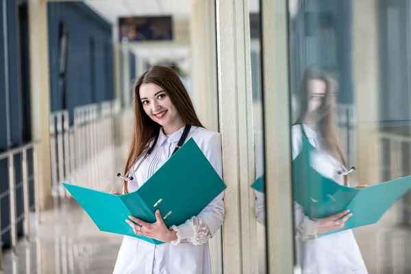 A beautiful young doctor is standing in the hospital corridor with a stethoscope around her neck. Concept of medicine. Doctor with a stethoscope. Portrait of a woman