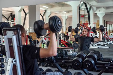 Genç sporcu spor salonunda dambılla egzersiz yapıyor. ağırlık egzersizleri konsepti