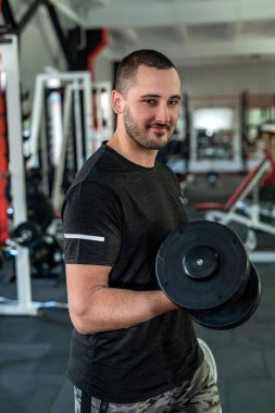 Genç sporcu spor salonunda dambılla egzersiz yapıyor. ağırlık egzersizleri konsepti