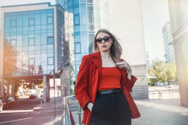 İş hayatında başarılı, takım elbiseli bir iş kadını kollarını kavuşturarak ofis binasının yanında duruyor. İş konsepti. Bir kadın portresi. Kadın patrondur. Kadın kariyeri