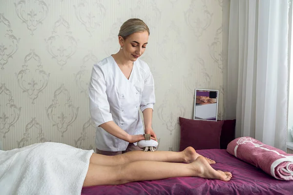 female therapist doing anti-cellulite medical massaging leg female client, wellbeing
