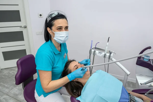 professional woman dentist performs a professional examination of the oral cavity in a beautiful woman. Health concept