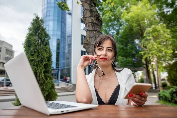 Young business woman at work in a laptop working on a terrace in a beautiful city. Online work concept. Work with laptop keys