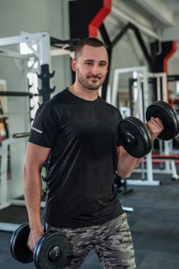 Genç beyaz bir adam spor salonunda dambıllarla antrenman yapıyor. etkin yaşam biçimi
