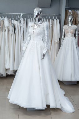 white wedding dresses on mannequin and away hanging on hangers in shop showroom 