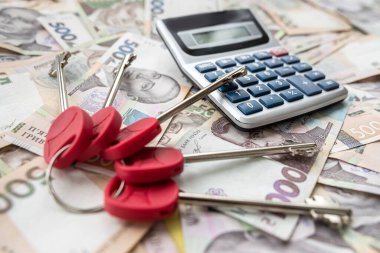 calculator house keys lying on ukraine papre money, uah. Finance or shopping concept