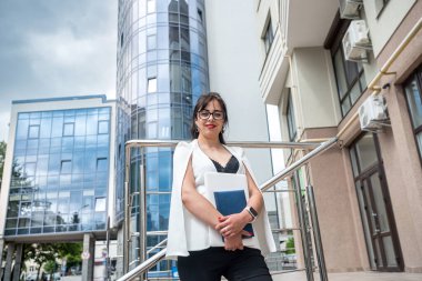 Şehrin ortasında zarif saçlı, klasik ceketli, ince, güzel bir bayan gülümsüyor. İş konsepti.