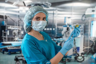 Çekici kadın doktor hasta için ameliyathanede şırınga tutuyor. İlaç. Ameliyathane doktorları ellerinde şırınga