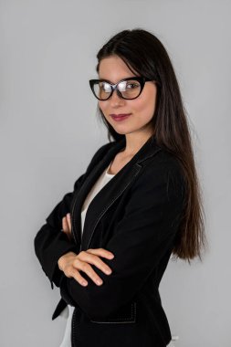Okuldaki küçük çocukların genç bayan öğretmeni gözlük takıyor ve izole bir arka planda kameraya gülümsüyor. Bir kızın portresi. Okulda öğretmen. Okula ilk gelişim.