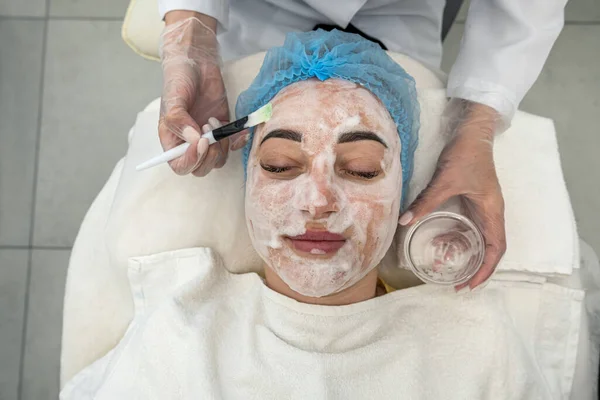 professional beautician performs ultrasonic cleaning of the skin of the face with the help of a device. Cosmetic procedure in the salon of the beauty clinic. The concept of machine cosmetology.