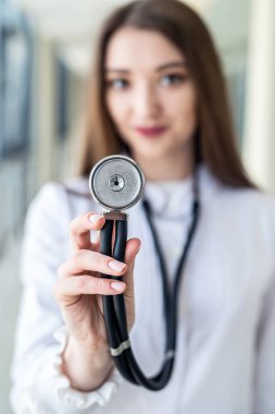 Koridorda steteskoplu mutlu, genç hemşire gülümsüyor. Tıp kavramı