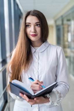 young experienced pediatrician doctor with patient log standing in hospital. Concept of medicine. The pediatrician is a woman. Portrait of a woman