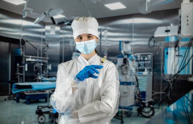 Kadın doktor ya da asistan ameliyat odasında mavi üniforma giyip şırıngayla ilaç taşıyor. Ameliyathane tıbbi personel kliniği personeli. Şırınga