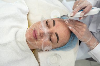 Maskeli profesyonel kadın kozmetik uzmanı kozmetoloji kliniğindeki kadın bir hastaya yüz hatları enjeksiyonu yapıyor. Güzel müşteri. kozmetoloji güzellik prosedürü