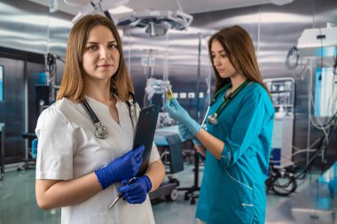 Ameliyathanede gülümseyen iki genç hemşire portresi. Tıp işçilerinin ilaçları