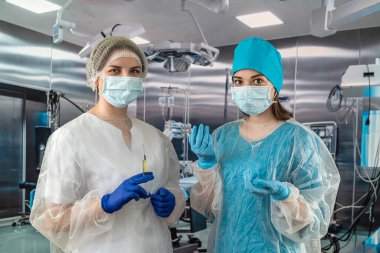 Genç bayan cerrah ve asistanı ameliyathanede bir hastayı bekliyorlar. İlaç. davranış tıbbi personel