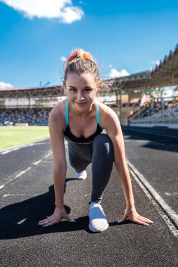 Esneme hareketleri yapan sportif bir kadın ya da stadyum pistinde yoga egzersizi yapan. Esneklik kavramı