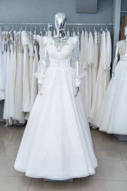white wedding dresses on mannequin and away hanging on hangers in shop showroom 