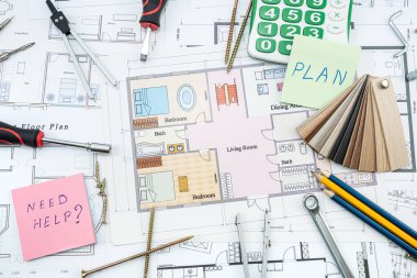 Bina planındaki yeni evlerin planlarının üzerine inşaat araçları saçılmış. Ev onarım servisi konsepti için bir model. Üst görüş nesneleri. İnşaat çalışmaları