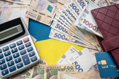 Ukraine national flag with UAH paper money in wallet, credit card calculator, finance concept, wealthy
