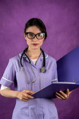 Elinde steteskopla gülümseyen kadın doktor ve arka planda izole edilmiş poz veren kitaplar. Kadın doktor konsepti. Bir kadın portresi