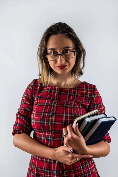 Smiling beautiful young brunette woman wearing a casual white shirt posing holding a book. isolated on a background of solid colors. studio portrait