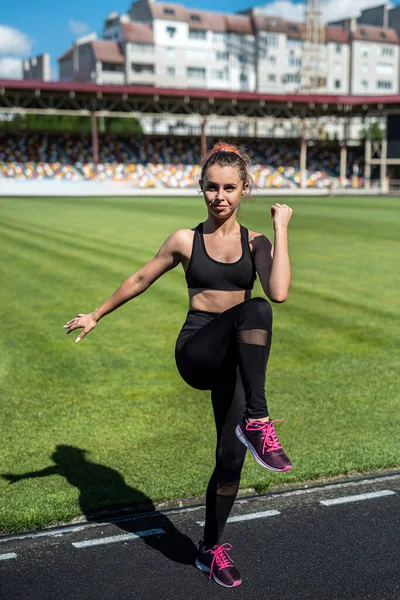 Pretty sporty young female coach doing stretching exercises at outdoor. sport for healthy lifestyle