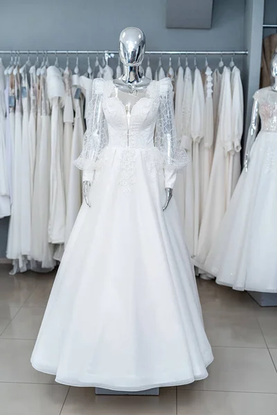 white wedding dresses on mannequin and away hanging on hangers in shop showroom