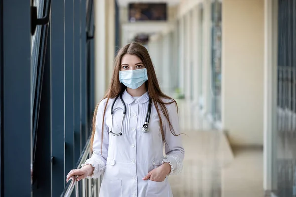 Portrait of female medical worker holding patient documents and stethoscope around neck in face mask and headgear for protection. The concept of medical workers. Portrait of a doctor