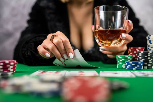 sexy woman with poker cards and chips in hands playing poker at the table. poker game a gambling woman in a dress with a neckline