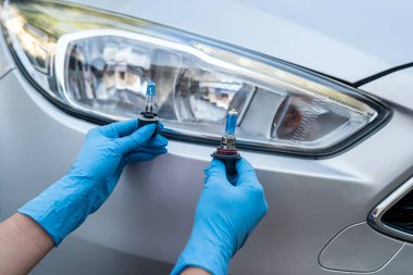 Güçlü tamircinin elleri halojen araba lambalarını farlara ve tamir arabasına dayar. Güçlü bir tamirci tarafından araba tamiri. Lamba elimde.