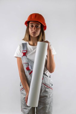 İnşaat işçisi üniformalı genç bir kadın ve kafasında beyaz arka planda izole edilmiş bir portre için poz veren bir kask var. Bir kadın portresi. İnşaatçı. mimar