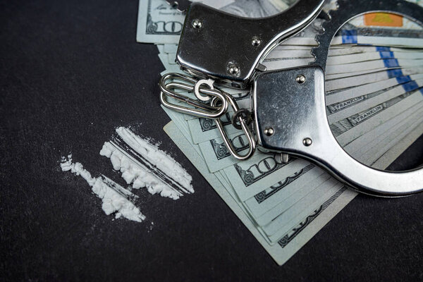 Plastic bags of cocaine or heroin and US dollar bills with handcuffs and bullets from a gun. violation of the law. Distribution of narcotics