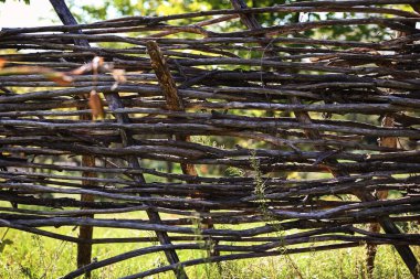 Doğal malzemelerden yapılmış, eski, otantik, zaman hasarlı bir çit. Hasır dallardan yapılmış, el yapımı.. 