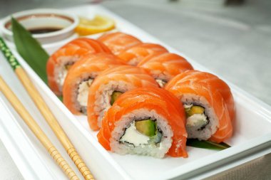 Philadelphia suşisi taze çiğ somon, krem peynir ve avokado ile yapılır. Teslimat için plastik bir konteynırda yuvarlanıyor. Lezzetli sağlıklı yemek..