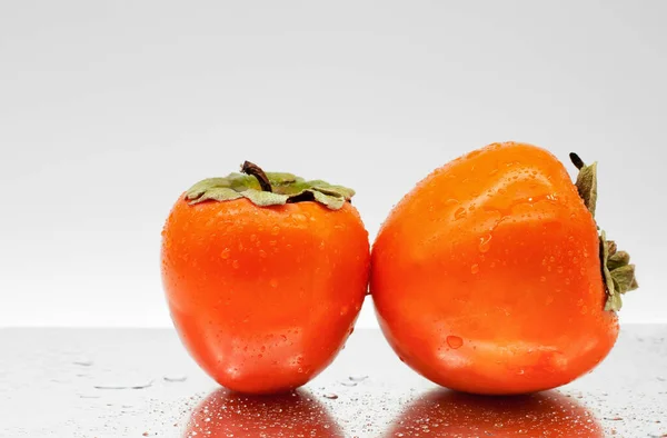 Aynalı bir yüzeyde iki hurma. Taze meyve ve su damlası. Yakın plan. Hafif arkaplan.