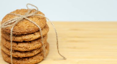 Ahşap bir yüzeyde ev yapımı yulaf ezmeli kurabiyeler. Kurabiyeler iple bağlanmış. Uzayı sağa kopyala. Ev yapımı kurabiyeler..