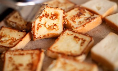 Tavada kızartılmış, kare şeklinde leziz kıtır ekmek. Ev yemeği, kahvaltı. Tereyağlı tavada kızartılmış yumurta içinde beyaz ekmek. Ev mutfağı. Kızarmış ekmekler çatalla döner..