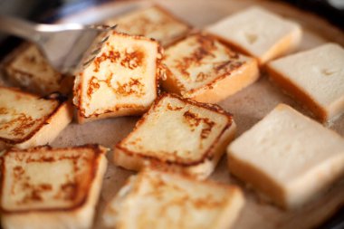 Tavada kızartılmış, kare şeklinde leziz kıtır ekmek. Ev yemeği, kahvaltı. Tereyağlı tavada kızartılmış yumurta içinde beyaz ekmek. Ev mutfağı. Kızarmış ekmekler çatalla döner..