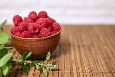 Kil kasede taze organik ahududu. Bambu hasırı, yeşil nane filizi, metin için boşluk