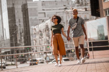 Sokakta yürüyen ve el ele tutuşan esmer tenli çift.