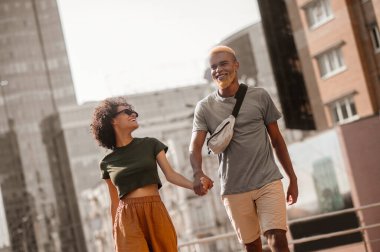 Sokakta yürüyen ve el ele tutuşan esmer tenli çift.