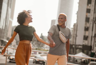 Sokakta yürüyen ve el ele tutuşan esmer tenli çift.