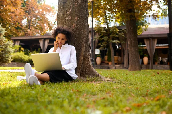 Mladá žena s laptopem sedícím pod stromem s laptopem — Stock fotografie