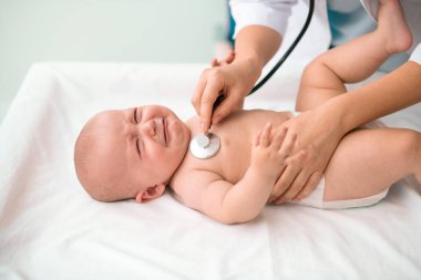 Tıbbi muayeneden geçen beyaz bir bebek.