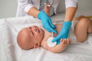Sağlık uzmanı kanepeye bebek enjekte ediyor.