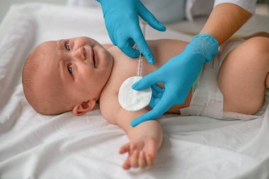 Korkmuş bebeğe bir doktor tarafından aşı enjekte ediliyor.